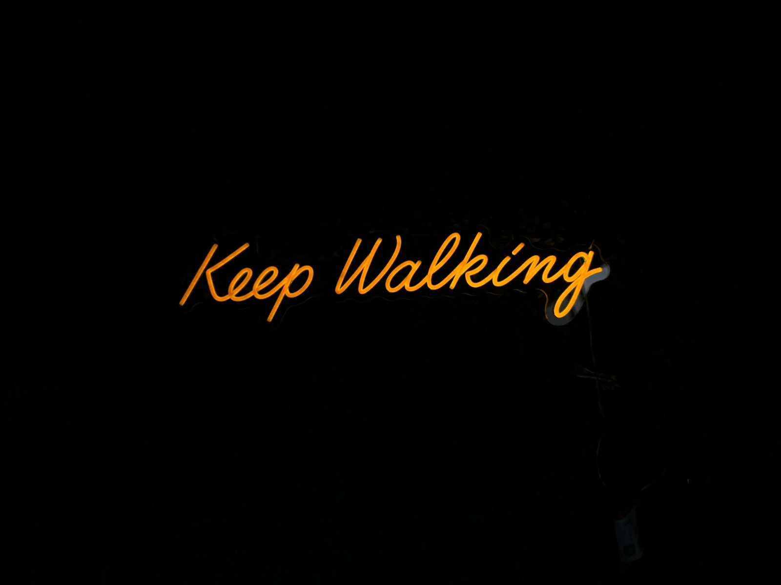 Neonbord met het woord Keep Walking in oranje schrijfletters