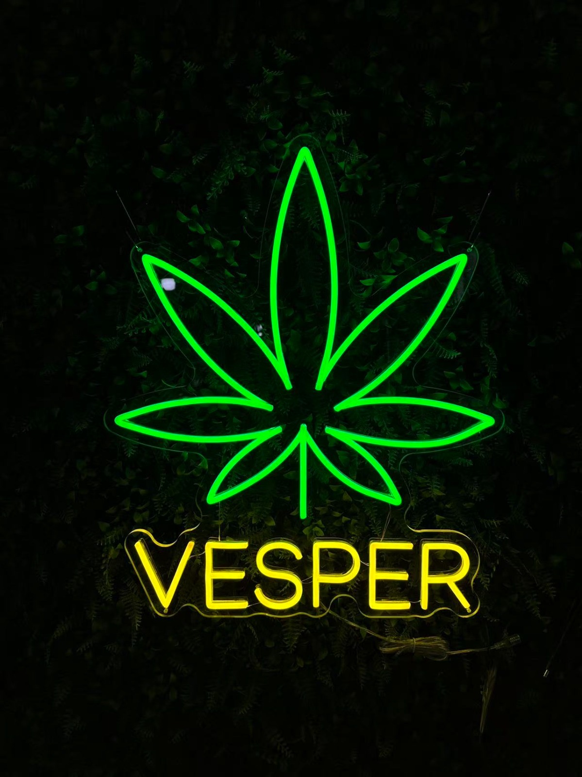 Neonbord met een groen blad en de naam Vesper in geel